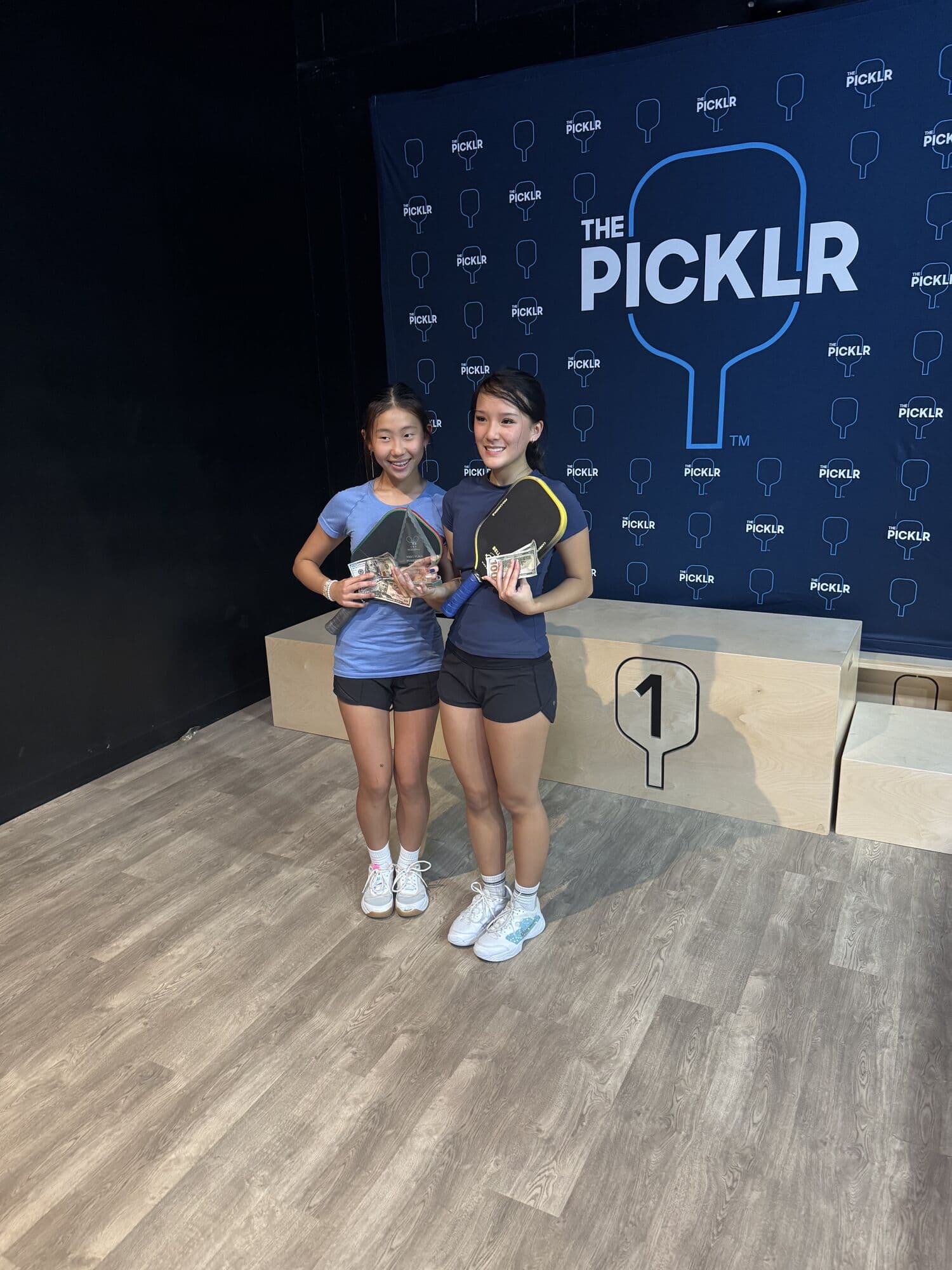 Two champions with their paddles on the top step of the podium