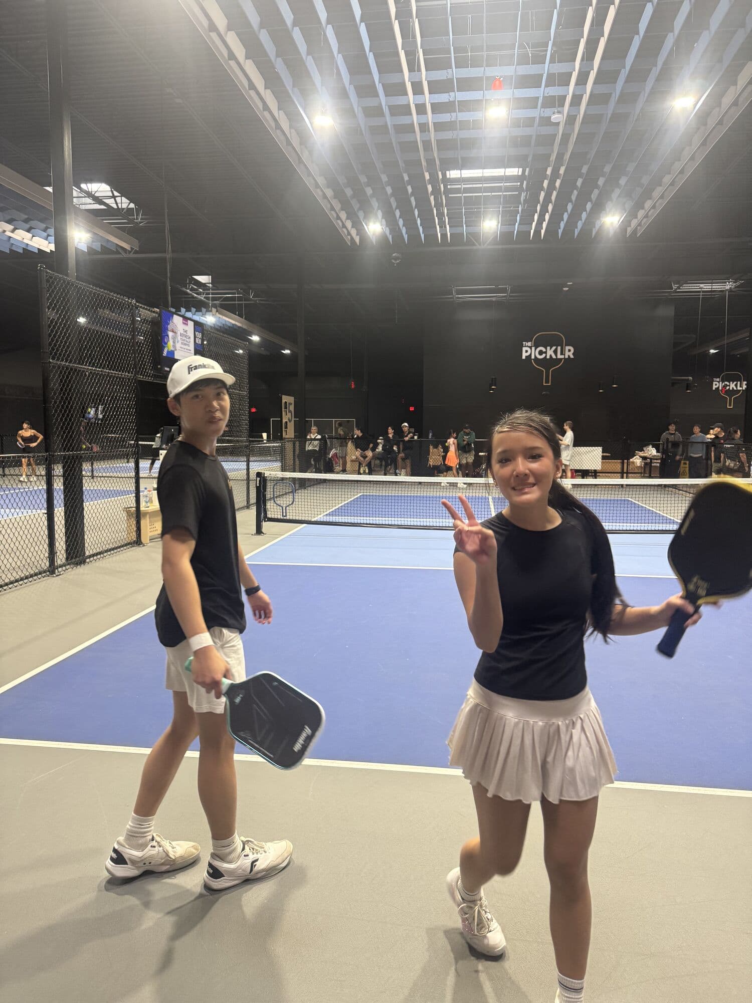 Mixed doubles partners smiling on court after a match